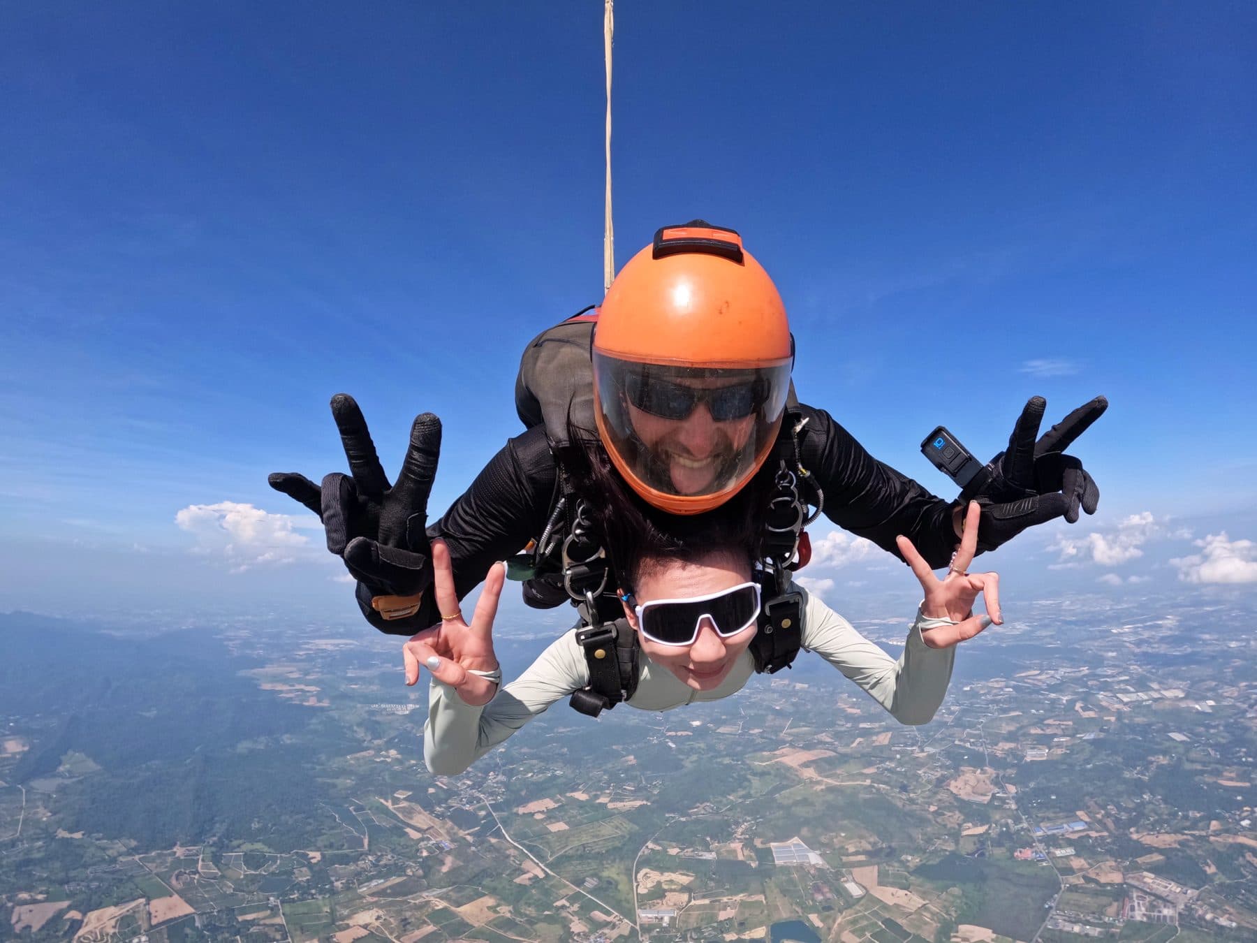 Instructor and passenger flashing peace signs at the camera in freefall