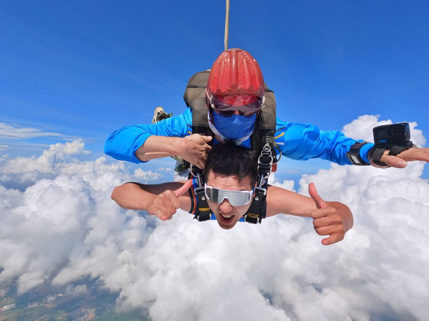 Instructor and passenger giving thumbs up in freefall above the clouds