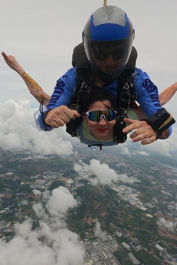 Tandem pair in freefall above scattered clouds