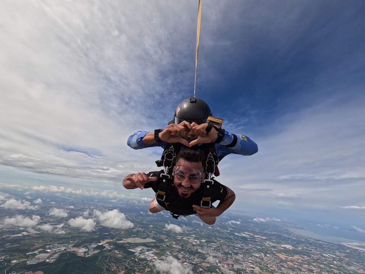 Tandem pair in freefall, instructor making a heart with his hands